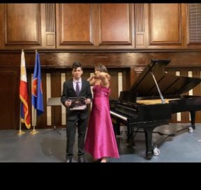 A student recognized beside Jean and a grand piano at a recital